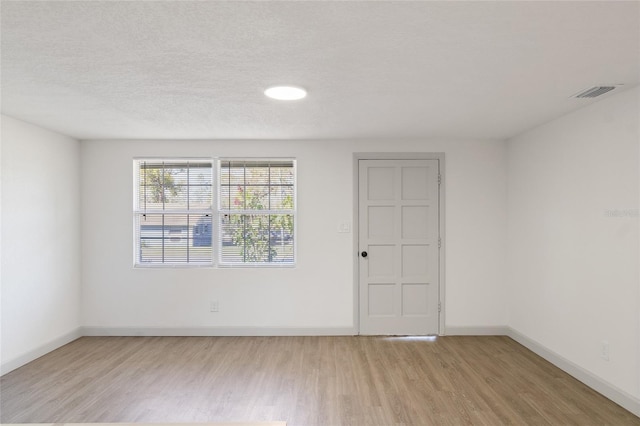 empty room with light hardwood / wood-style flooring and a textured ceiling