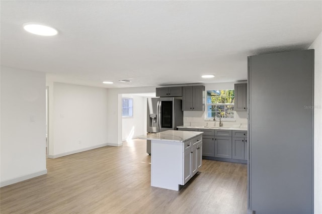 kitchen featuring sink, light hardwood / wood-style flooring, stainless steel fridge, gray cabinets, and a kitchen island