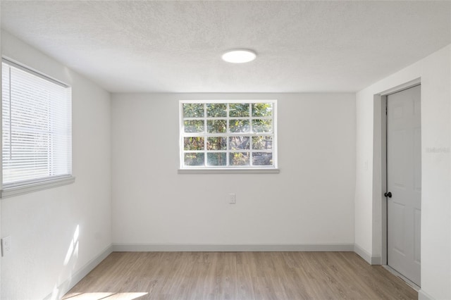 spare room with light hardwood / wood-style floors and a textured ceiling