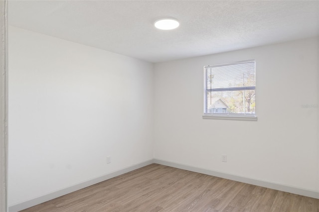 spare room featuring a textured ceiling and light wood-type flooring