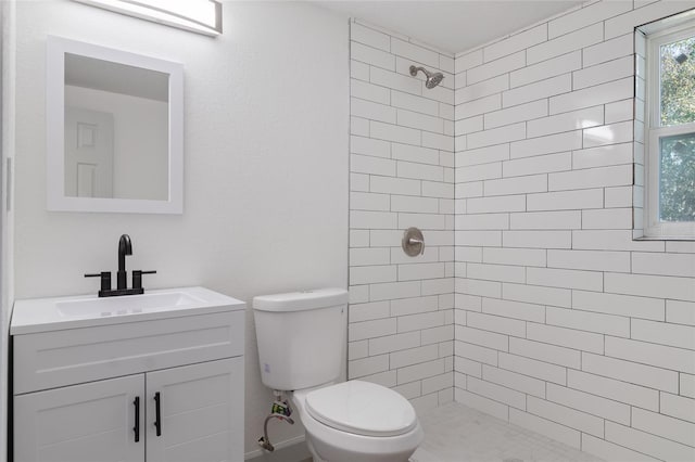 bathroom featuring a tile shower, vanity, and toilet