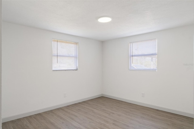 empty room with light wood-type flooring, a textured ceiling, and a wealth of natural light