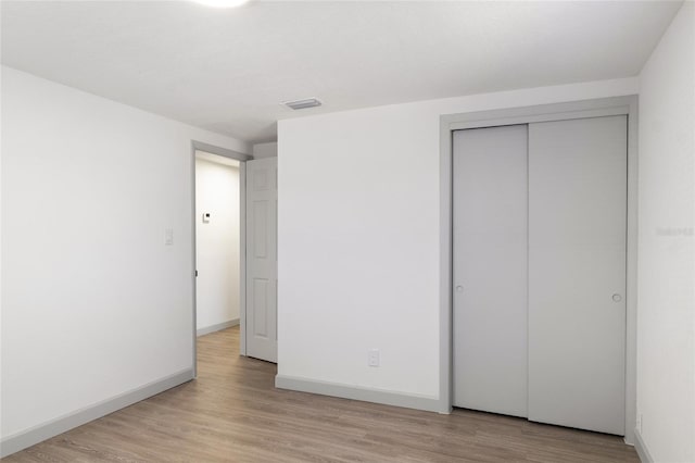 unfurnished bedroom with light hardwood / wood-style flooring and a closet