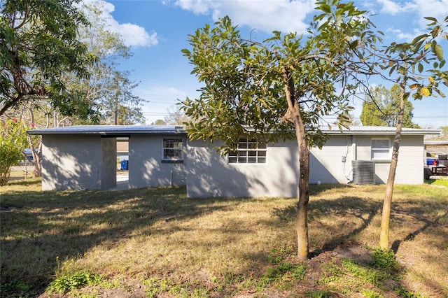 back of property featuring cooling unit and a lawn