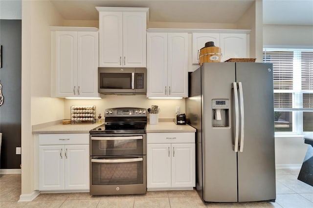 kitchen with light tile patterned flooring, white cabinetry, and stainless steel appliances