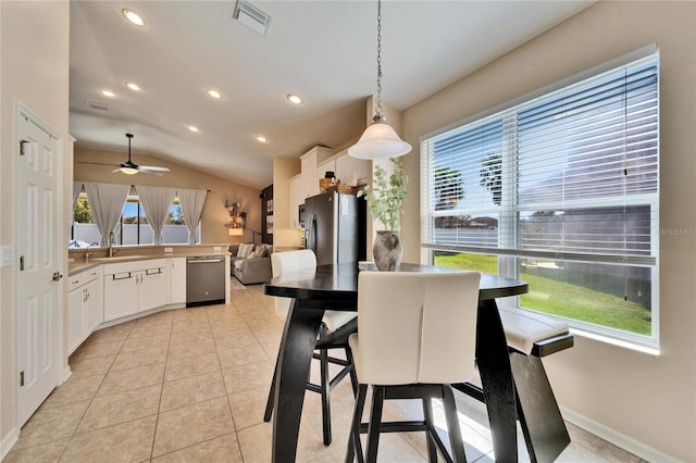 dining room featuring sink, vaulted ceiling, and light tile patterned flooring