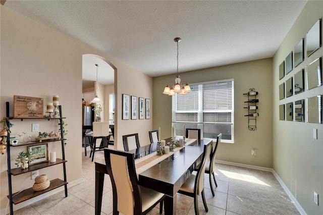 tiled dining area featuring a chandelier and a textured ceiling