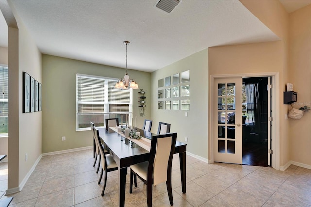 tiled dining room with an inviting chandelier and a textured ceiling