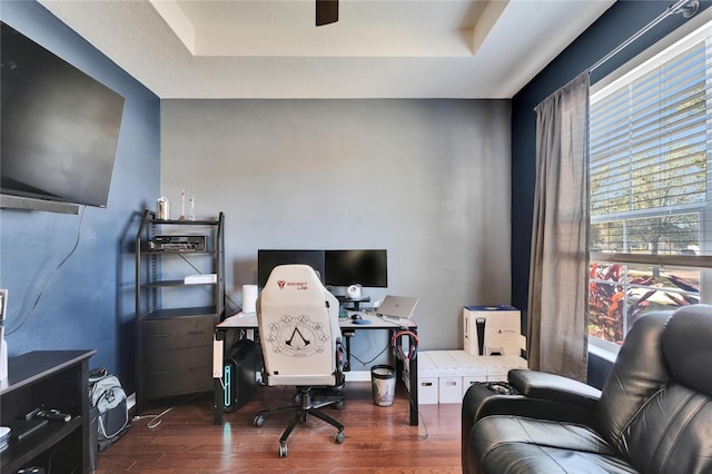 office area featuring a tray ceiling, dark hardwood / wood-style flooring, and ceiling fan