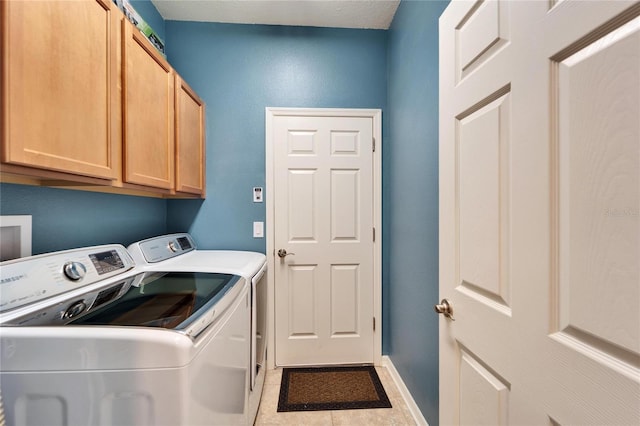 laundry room featuring independent washer and dryer, light tile patterned floors, and cabinets