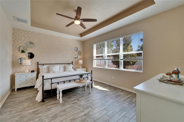 bedroom with a tray ceiling, ceiling fan, and light hardwood / wood-style floors