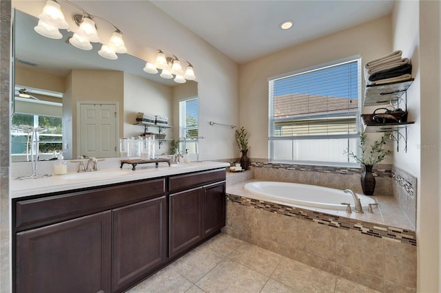 bathroom featuring tile patterned flooring, tiled tub, vanity, and a wealth of natural light