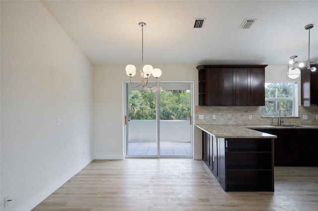 kitchen featuring dark brown cabinetry, decorative light fixtures, sink, and decorative backsplash