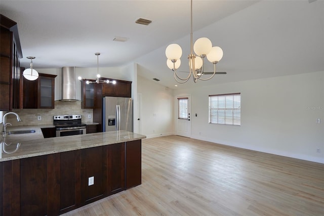 kitchen with appliances with stainless steel finishes, sink, kitchen peninsula, wall chimney range hood, and an inviting chandelier