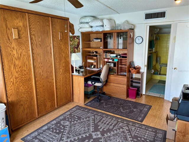 office area featuring a textured ceiling, wood finished floors, visible vents, and ceiling fan