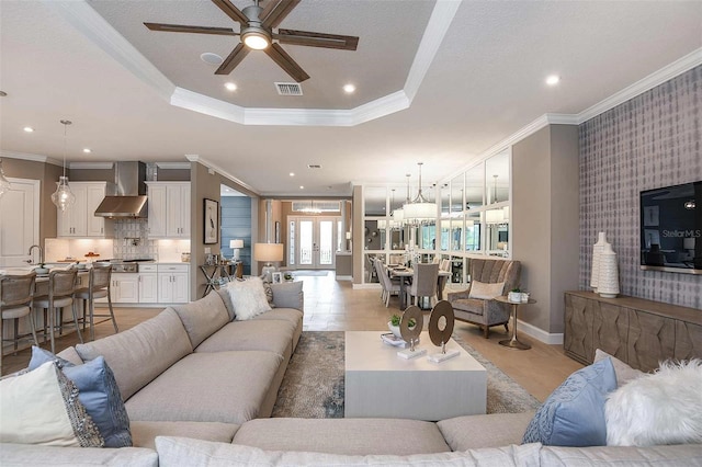 living room with ornamental molding, a tray ceiling, and ceiling fan with notable chandelier