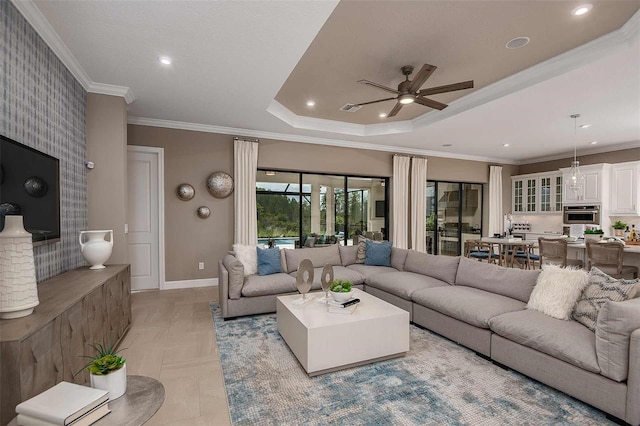 living room with a raised ceiling, ornamental molding, and ceiling fan