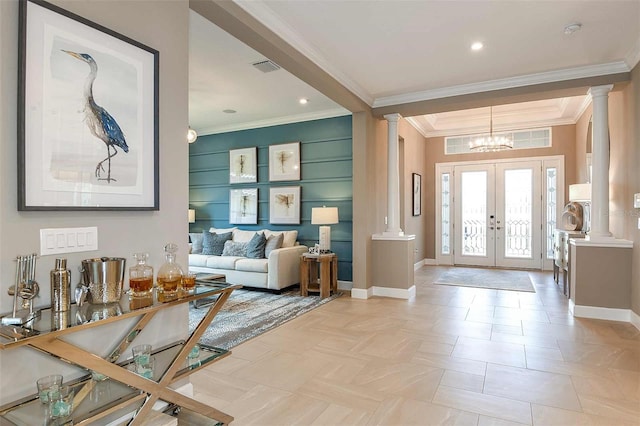 foyer featuring french doors, ornamental molding, a chandelier, and ornate columns