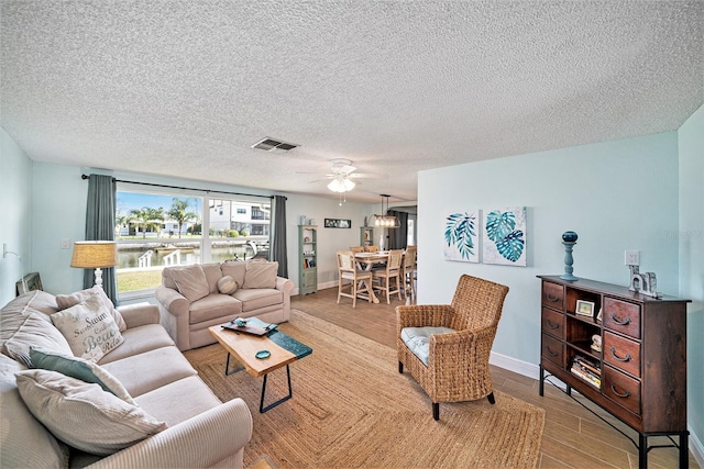 13614 Evelane Dr, Hudson, FL 34667 - living room with light wood finished floors, ceiling fan, a textured ceiling, a water view, and baseboards