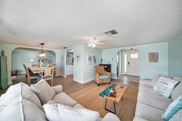 13614 Evelane Dr, Hudson, FL 34667 - living room with arched walkways, a ceiling fan, a textured ceiling, wood finished floors, and baseboards