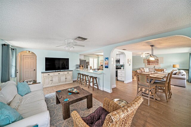13614 Evelane Dr, Hudson, FL 34667 - living room with a ceiling fan, arched walkways, a textured ceiling, light wood-style floors, and baseboards