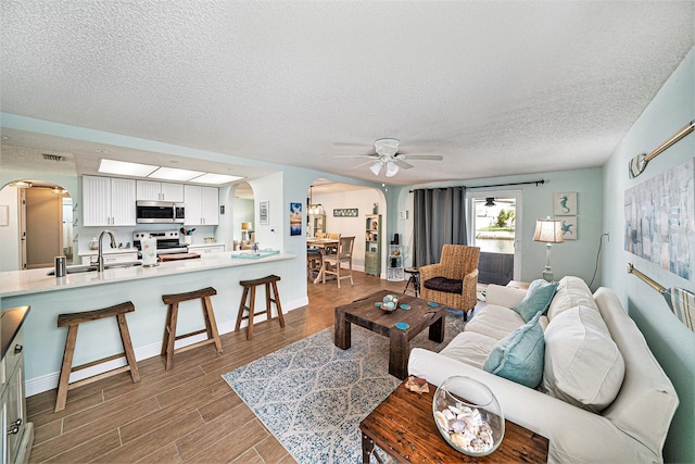13614 Evelane Dr, Hudson, FL 34667 - living area featuring arched walkways, ceiling fan, wood finished floors, and a textured ceiling