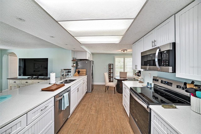 13614 Evelane Dr, Hudson, FL 34667 - kitchen with appliances with stainless steel finishes, a sink, light wood-style floors, light countertops, and white cabinetry