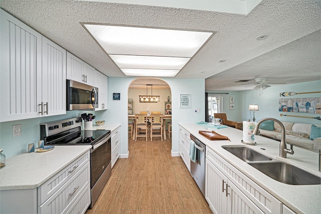 13614 Evelane Dr, Hudson, FL 34667 - kitchen featuring stainless steel appliances, a sink, light wood-type flooring, light countertops, and arched walkways