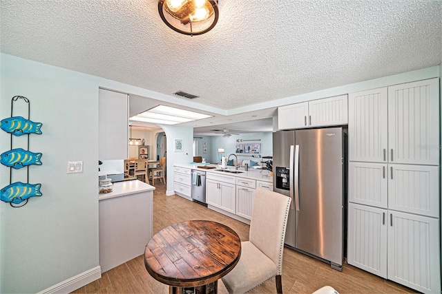 13614 Evelane Dr, Hudson, FL 34667 - kitchen featuring appliances with stainless steel finishes, arched walkways, light wood finished floors, light countertops, and a sink