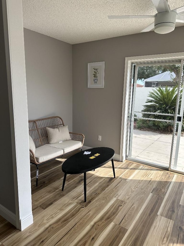 sitting room featuring a textured ceiling, baseboards, and light wood-style floors