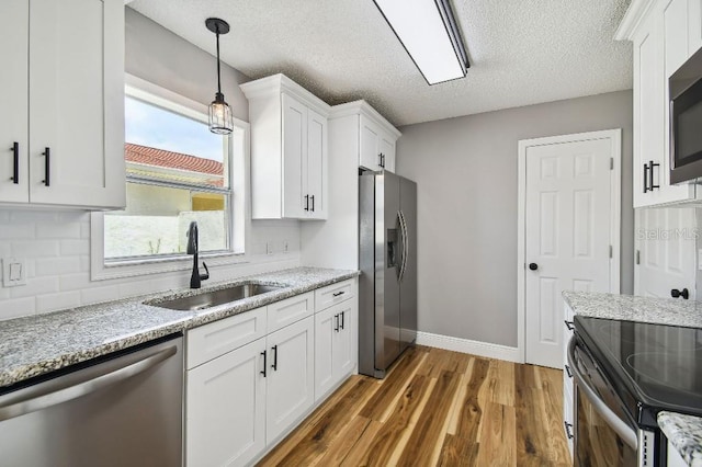 kitchen featuring white cabinetry, stainless steel appliances, a sink, and wood finished floors