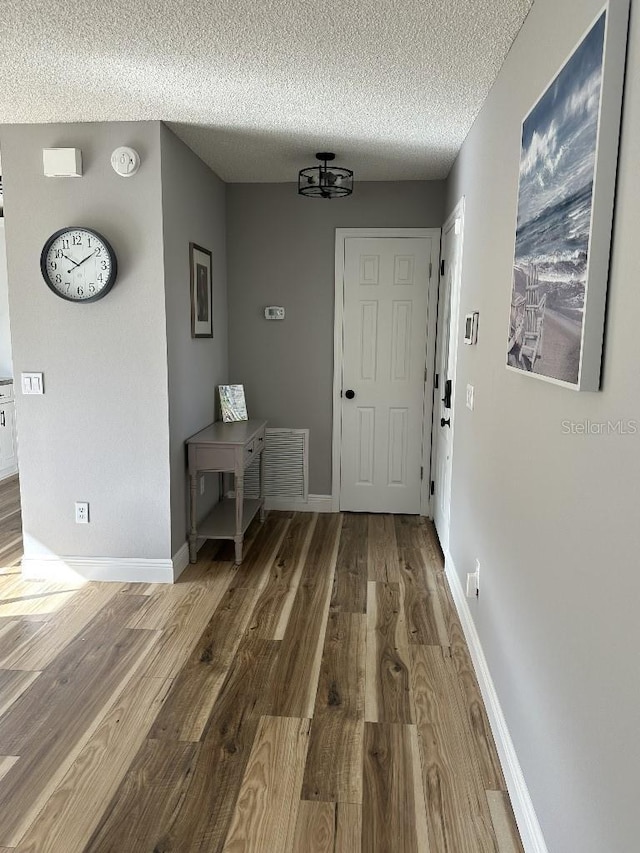 interior space featuring a textured ceiling, wood finished floors, and baseboards