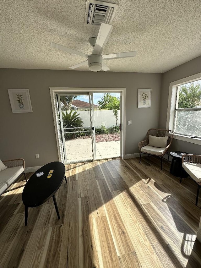 sitting room with visible vents, a ceiling fan, a textured ceiling, wood finished floors, and baseboards