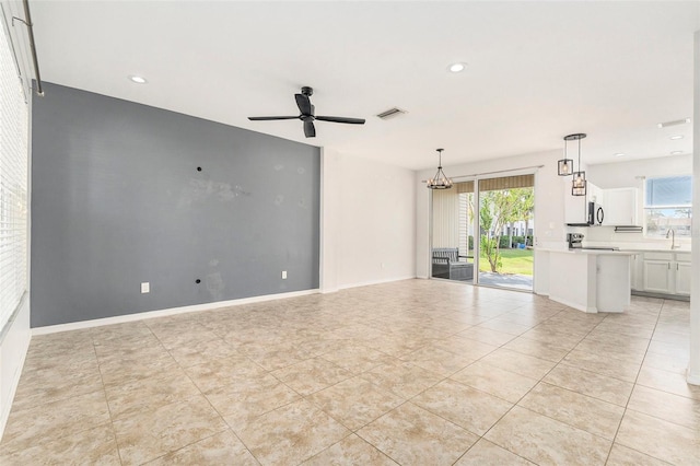 unfurnished living room with a sink, plenty of natural light, visible vents, and a ceiling fan