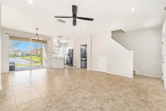 unfurnished living room with recessed lighting, visible vents, baseboards, a water view, and ceiling fan with notable chandelier