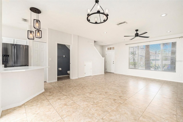 unfurnished living room with ceiling fan with notable chandelier, baseboards, visible vents, and recessed lighting