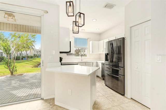 kitchen featuring stainless steel appliances, light countertops, hanging light fixtures, white cabinetry, and a peninsula