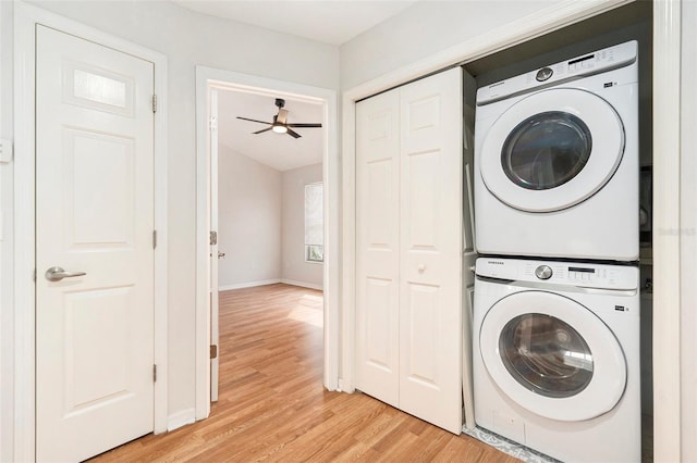 laundry area featuring baseboards, laundry area, stacked washer / dryer, and light wood-style floors