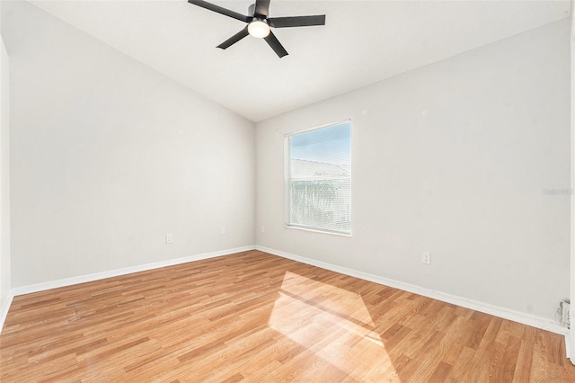 empty room featuring ceiling fan, light wood finished floors, vaulted ceiling, and baseboards