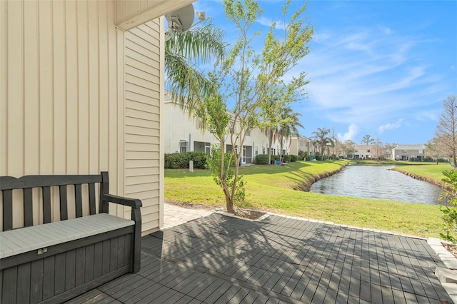 wooden terrace featuring a residential view, a water view, and a lawn