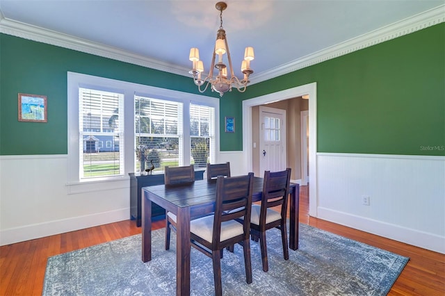 dining room featuring a chandelier, wood finished floors, and wainscoting