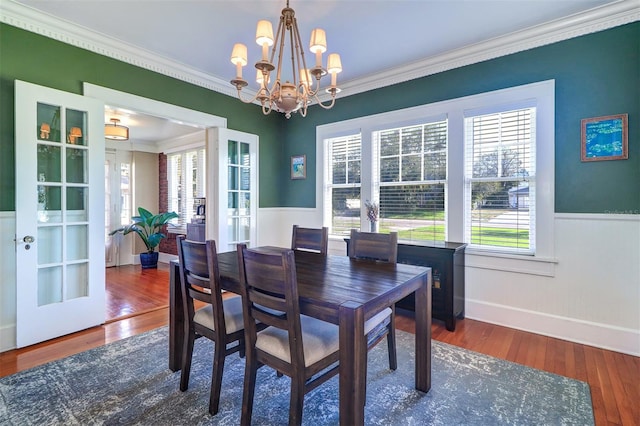 dining area featuring ornamental molding, wainscoting, and wood finished floors