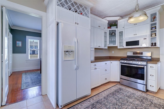 kitchen featuring dark countertops, white appliances, white cabinets, and crown molding