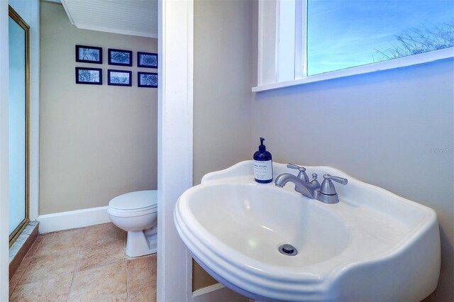 bathroom featuring a stall shower, baseboards, toilet, tile patterned flooring, and a sink