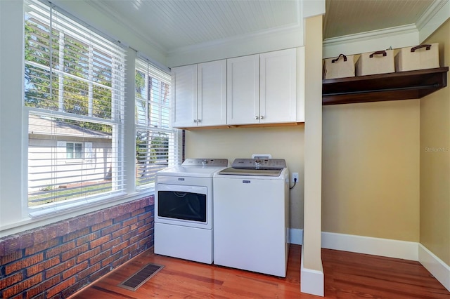 laundry area with ornamental molding, washing machine and dryer, cabinet space, and visible vents