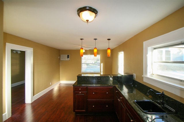 kitchen with baseboards, dark wood-style floors, decorative light fixtures, a sink, and a wall mounted AC