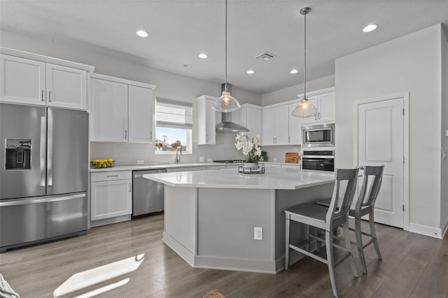 kitchen featuring a kitchen island, pendant lighting, white cabinets, a kitchen bar, and stainless steel appliances