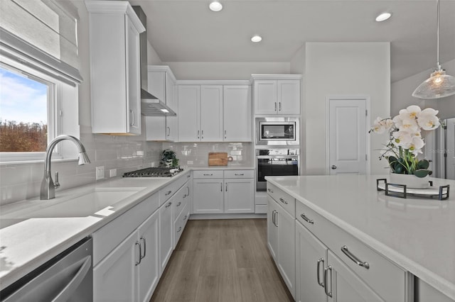 kitchen featuring sink, hanging light fixtures, stainless steel appliances, decorative backsplash, and white cabinets