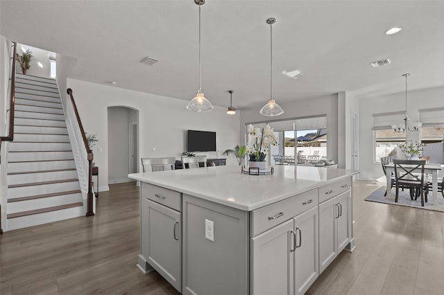 kitchen featuring pendant lighting, wood-type flooring, white cabinets, and a kitchen island