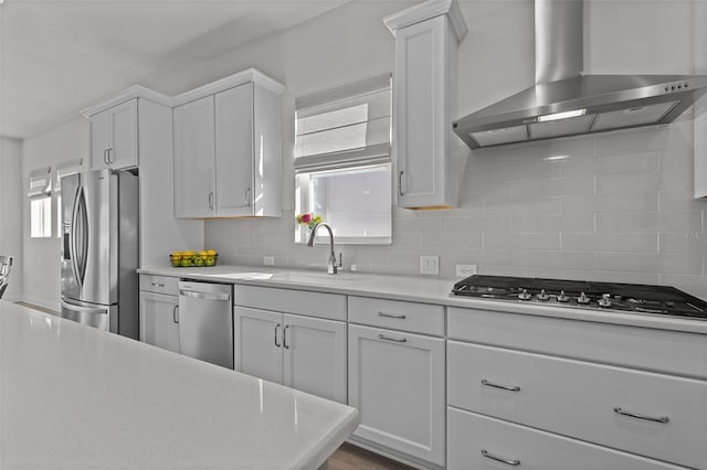 kitchen featuring appliances with stainless steel finishes, sink, white cabinets, and wall chimney exhaust hood